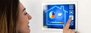 Dieses Foto zeigt eine Frau die einen digitalen Monitor im SmartHome bedient und dient als Titelbild für Lösungen rund um das Thema Klimaautomation in Industriehallen.