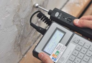 Das Foto zeigt ein Messgerät in verwendung, wie es auch die UvS Umweltanalytik nutzt um Bauwerksfeuchtigkeit zu messen, da zu hohe Werte Schimmelbildung begünstigen können.